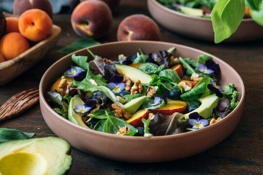 Peach salad with avocado, blueberries, walnuts and pansy flowers
