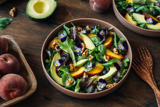 Peach salad with avocado, blueberries, walnuts and pansy flowers