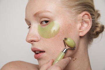 Model with green jade roller and under-eye patch