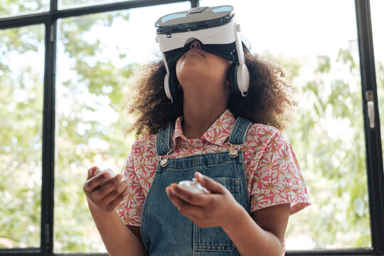 Child using virtual reality glasses and joysticks indoors