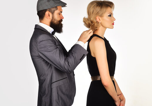Couple in evening clothes. Stylish man helps woman dressing up.
