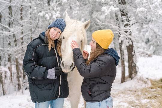 young women  with white pony in the snow