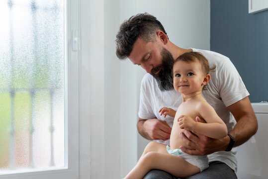 Father changing clothes of toddler in bathroom