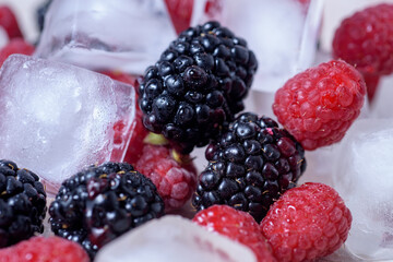 Fresh blackberries and raspberries in ice, close-up