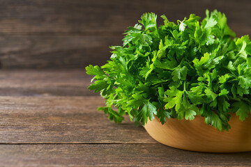 fresh parsley in a wooden bowl on the table, copy space for text.
