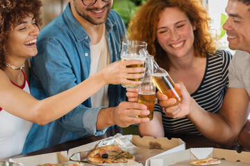 Multiethnic Group Of Young People Having Fun, Eating Pizza And Drinking Beer Together. 