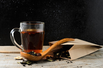 A glass mug of fragrant brewed flower tea on a wooden table, with a wooden spoon