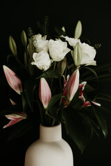 Naklejka na ściany i meble Rose and lily flower bunch in a vase on black background. 