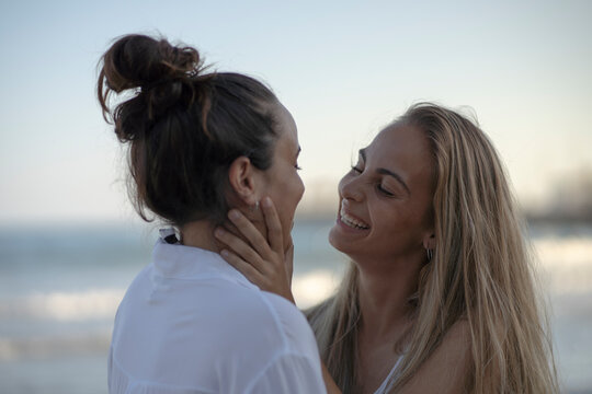 A couple of woman kissing on the beach on a summer day.