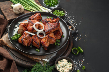Shish kebab on a platter with onions on a black background. Meat dish.