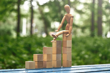 pyramid made from wooden toy blocks and wooden man on nature background