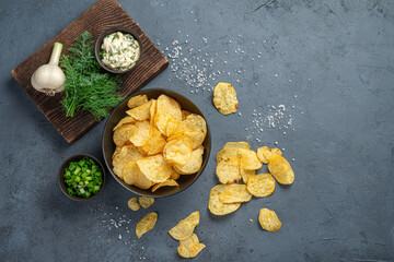 Potato chips on a dark gray background with ingredients.