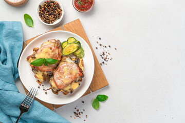 Baked chicken breast with mushrooms, vegetables and cheese on a light background.