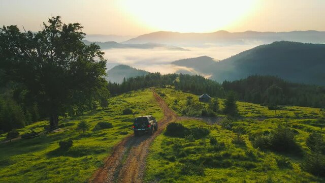Dawn in the mountains covered with fog. Tourists descending from the mountains by car. Beautiful trip to the magical mountains at sunrise.