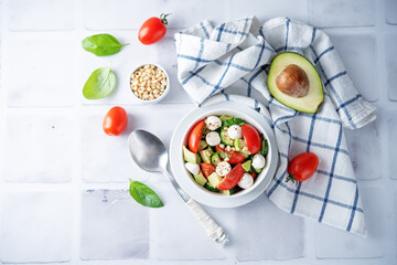 Cucumber tomato avocado mozzarella salad in a bowl