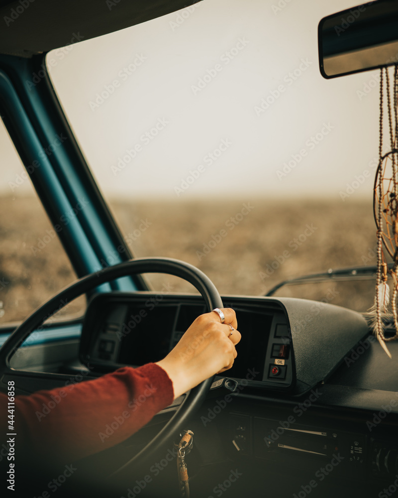 Wall mural caucasian girl holds the steering wheel driving a vintage and camper van around an island with volca