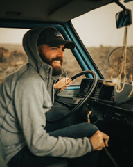 Caucasian boy driving a vintage van around Lanzarote island in February with volcanic landscape and...