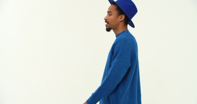 Young black man in blue sweater showing no gesture while walking past camera isolated 