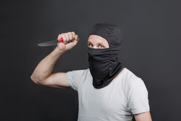 Metal knife in the hand of caucasian man in black mask. The criminal with a knife weapon threatens to kill. With space for an inscription. News staties, newspaper, social issues. american man