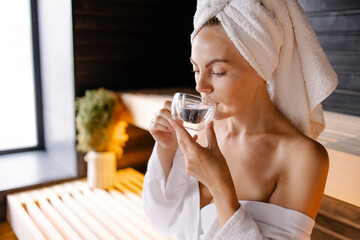 Woman sits on spa in a sauna resting procedure. Hot steam relaxation. Sweaty skin detox therapy....