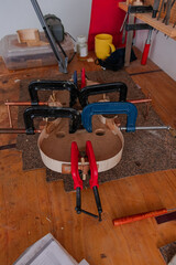 Luthier is using grippers to give shape to violin body