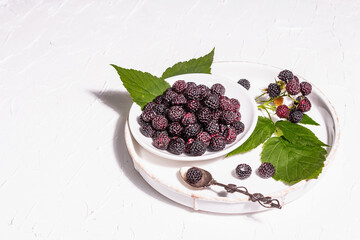 Black raspberry in a white bowl. Ripe organic fruits on the white putty background