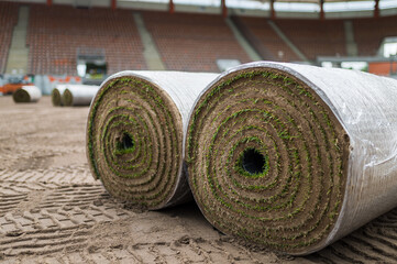 Big rolls of grass lays on a football field at the stadium.