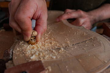 Luthier is using a little tool to give shape the violin body  