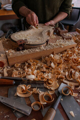 Luthier is using a little tool to give shape the violin body  