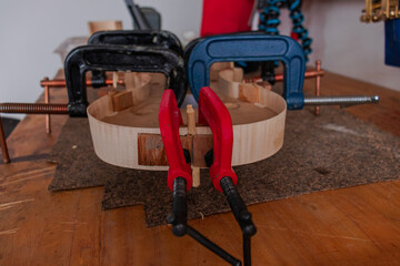 Luthier is using grippers to give shape to violin body