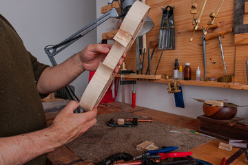 Luthier is checking how is going the violin's mold 