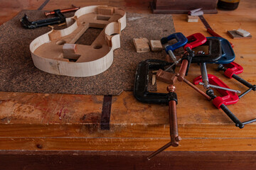 Luthier is using grippers to give shape to violin body