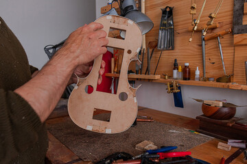 Luthier is checking how is going the violin's mold 