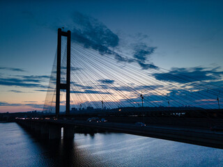 Fototapeta premium Aerial view from a drone on a cable-stayed bridge on a river in the evening