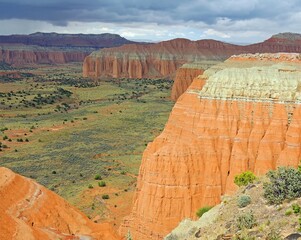 looking out at colorful eroded cliffs from upper cathedral valley overlook with storm clouds ,...