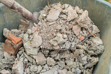 Pile of construction waste from broken bricks, mortar and concrete. Construction debris in the wheelbarrow and on the shovel.
