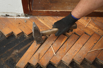 Worker removing old damaged parquet using hammer tool
