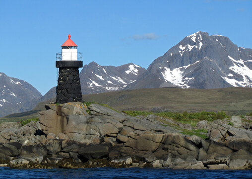  lighthouse, birds on the rocks,  and  snowy mountains  on a sunny day near leknes in the lofoten islands, nordland, norway     