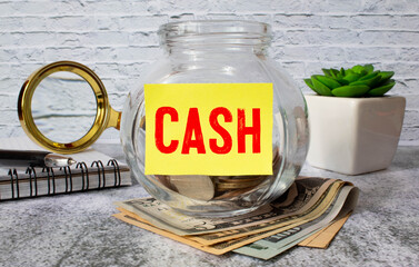 The word CASH is written on wooden cubes near a calculator on a banknotes background. Financial concept