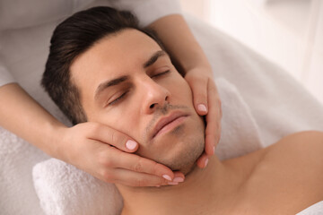 Fototapeta na wymiar Man receiving facial massage in beauty salon, above view