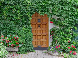 Front door of house surrounded by vines and flowers