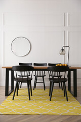 Stylish wooden dining table and chairs in room. Interior design