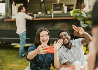 Multiracial friends having fun doing selfie eating at food truck outdoor - Focus on african man face
