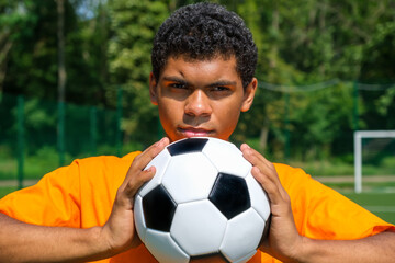 African-American man holds soccer ball close up while standing on sports court