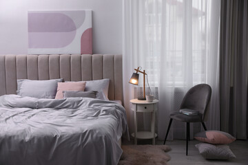 Cozy bed with soft silky bedclothes in light room