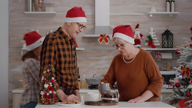 Grandparents with granddaughter greeting remote mother celebrating xmas holiday during online videocall meeting using mobile. Family wearing santa kat enjoying christmas winter season