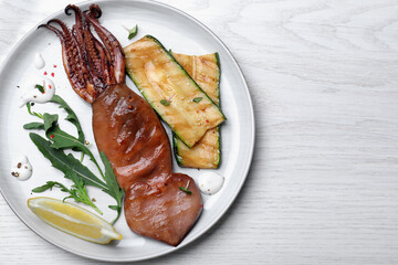Delicious grilled squid served on white wooden table, top view. Space for text