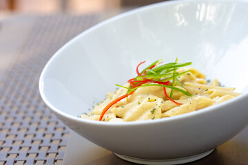 Side Shot of A Creamy Penne Pasta Alfredo With Julienned Bell Peppers On Top As Garnish.