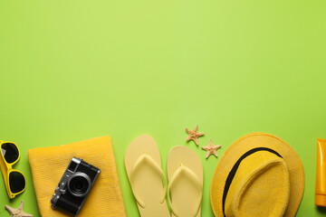 Flat lay composition with different beach objects on green background, space for text