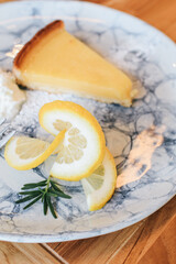 Lemon tart. Healthy dessert plate with delicious citrus cake, fork on table wooden table. A baking dish with a custard lemon filling decorated.Tasty fruit dessert. Vertical, selective focus.